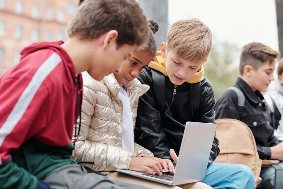 Group of teenagers studying together on a laptop outdoors, fostering collaboration