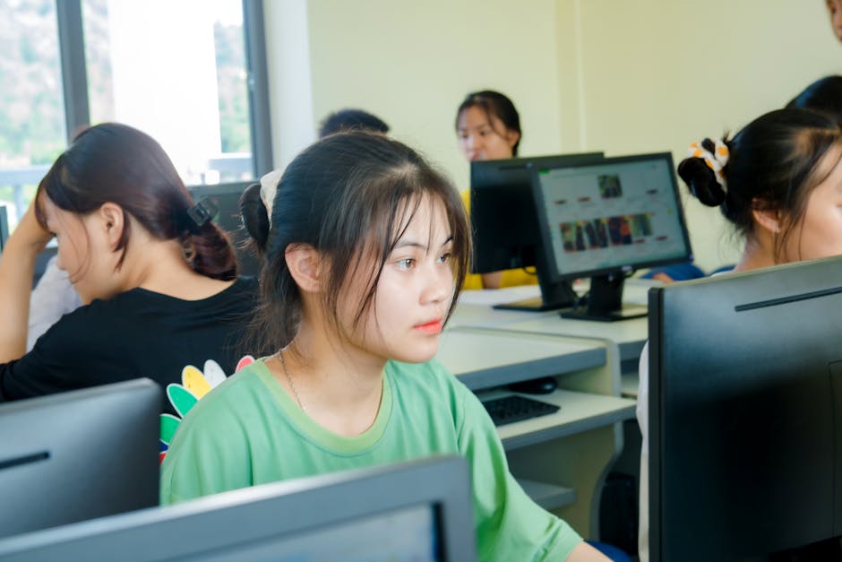 Asian students focused on studying technology in a bright computer classroom setting